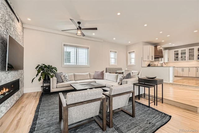 living area with light wood-type flooring, a fireplace, baseboards, and recessed lighting