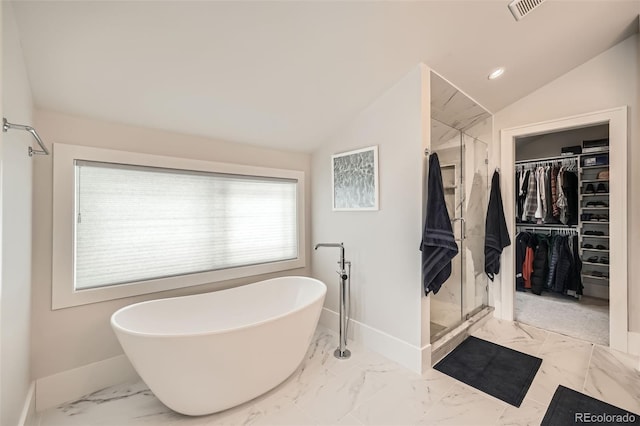 full bathroom featuring lofted ceiling, marble finish floor, a spacious closet, and a freestanding bath