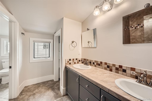 bathroom with tasteful backsplash, a sink, toilet, and double vanity