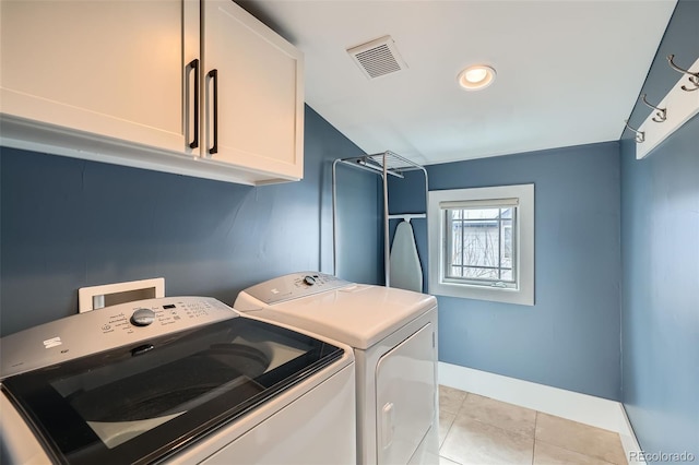 laundry room featuring washing machine and clothes dryer, light tile patterned floors, visible vents, cabinet space, and baseboards