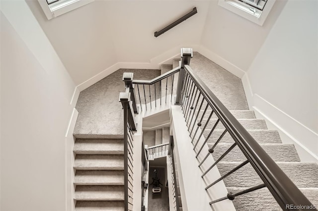 staircase with a skylight, carpet flooring, and baseboards