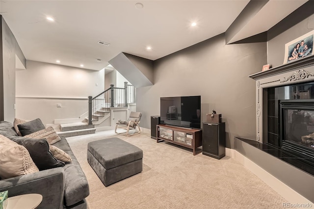 living area featuring baseboards, visible vents, a tiled fireplace, light colored carpet, and stairs