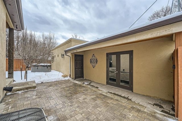 view of patio / terrace featuring french doors, fence, and a jacuzzi