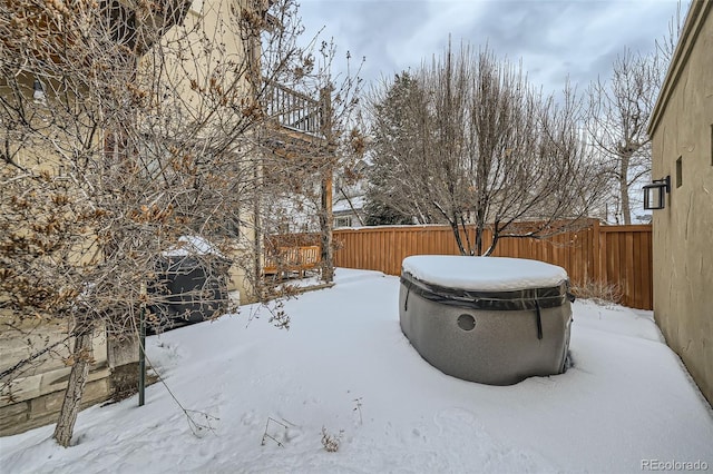 yard covered in snow with a fenced backyard and a hot tub