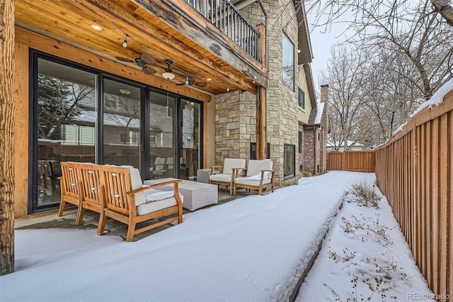 snow covered patio featuring a balcony, fence, and a ceiling fan