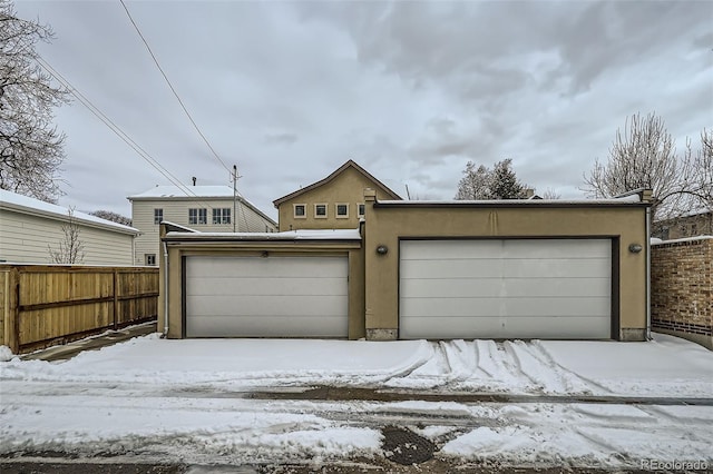 view of front of house featuring a garage, fence, and stucco siding