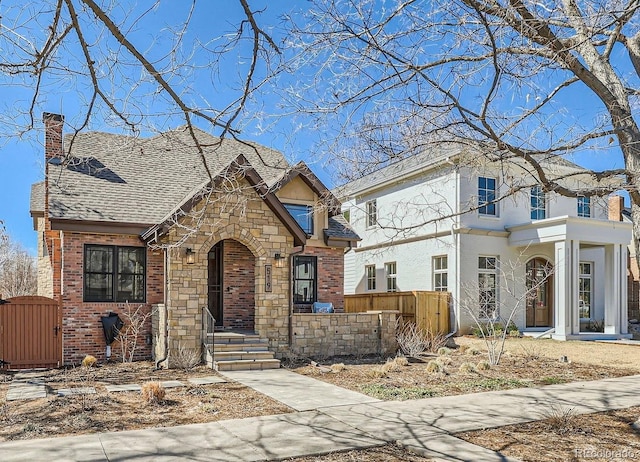 view of front of house with a gate, fence, roof with shingles, stucco siding, and a chimney