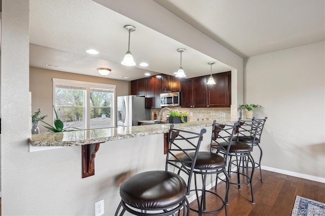 1095 W 69th Ave, Denver, CO 80221 - kitchen featuring appliances with stainless steel finishes, tasteful backsplash, a peninsula, a kitchen breakfast bar, and dark wood-style flooring
