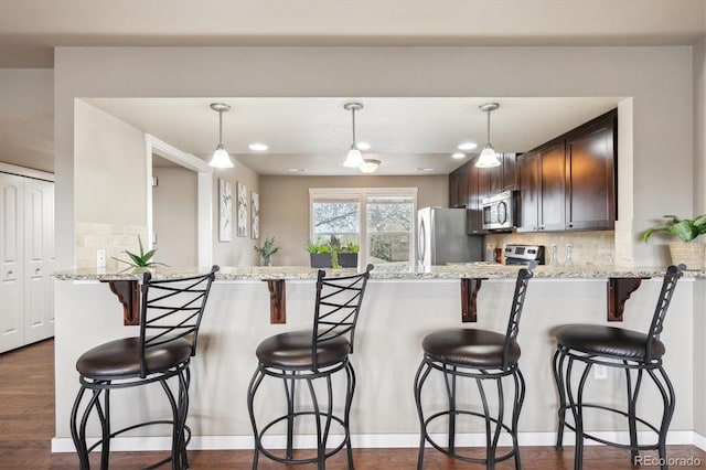 1095 W 69th Ave, Denver, CO 80221 - kitchen with appliances with stainless steel finishes, a peninsula, tasteful backsplash, and dark brown cabinets