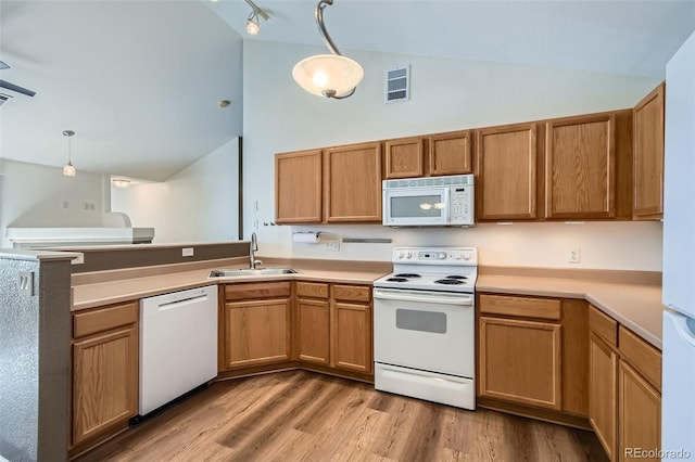 kitchen featuring a peninsula, white appliances, a sink, visible vents, and light wood finished floors