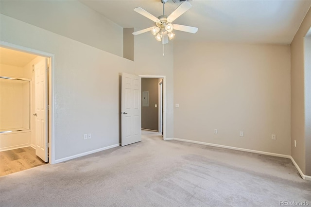 unfurnished bedroom featuring ceiling fan, light colored carpet, ensuite bathroom, and electric panel