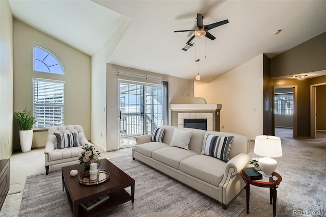 carpeted living area featuring high vaulted ceiling, a tile fireplace, visible vents, a ceiling fan, and baseboards