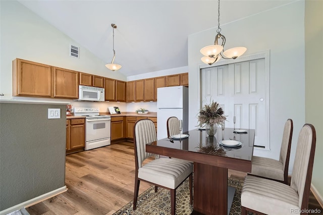 kitchen featuring decorative light fixtures, brown cabinets, visible vents, light wood-style floors, and white appliances