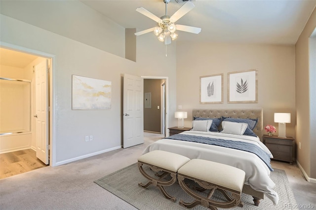 bedroom with high vaulted ceiling, baseboards, ensuite bathroom, and light colored carpet