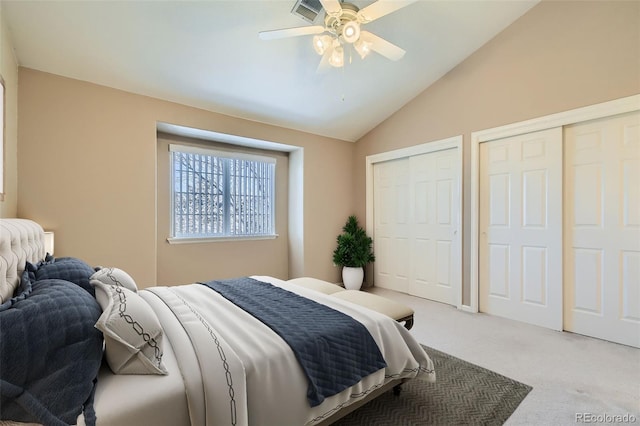 carpeted bedroom featuring ceiling fan, visible vents, vaulted ceiling, and two closets