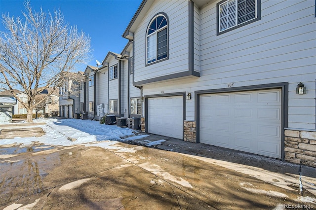 view of side of home with an attached garage and stone siding