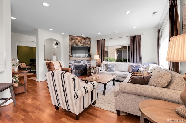 10152 Bluffmont Ln, Lone Tree, CO 80124 - living room featuring wood finished floors, arched walkways, recessed lighting, and a stone fireplace