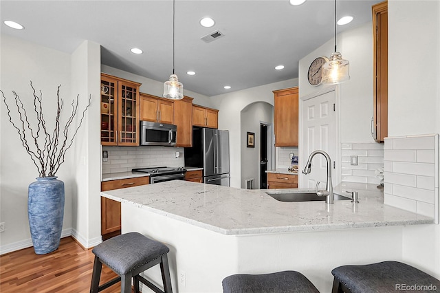 10152 Bluffmont Ln, Lone Tree, CO 80124 - kitchen with stainless steel appliances, a peninsula, recessed lighting, brown cabinetry, and light wood-style flooring