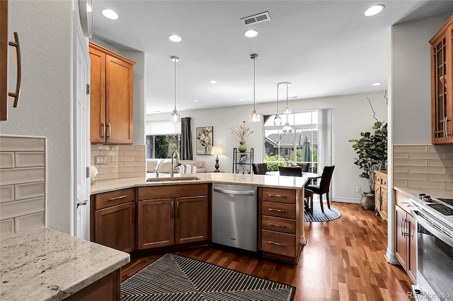 10152 Bluffmont Ln, Lone Tree, CO 80124 - kitchen with stainless steel appliances, a peninsula, dark wood-type flooring, backsplash, and decorative light fixtures
