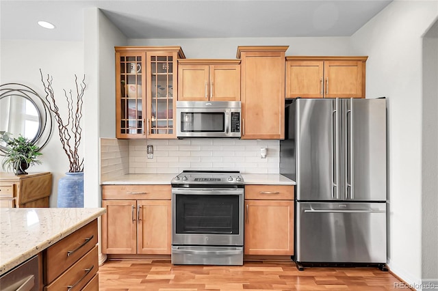 10152 Bluffmont Ln, Lone Tree, CO 80124 - kitchen featuring stainless steel appliances, light wood-style flooring, backsplash, glass insert cabinets, and light stone counters