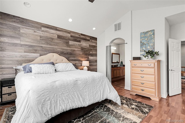 10152 Bluffmont Ln, Lone Tree, CO 80124 - bedroom featuring an accent wall, wood finished floors, recessed lighting, wood walls, and ensuite bath