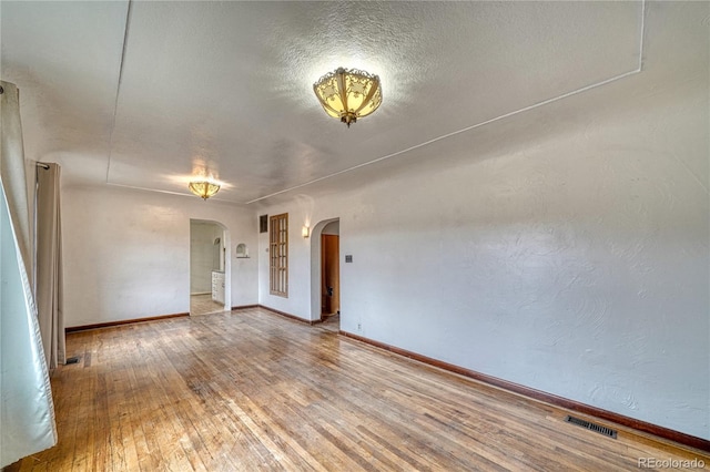 unfurnished room with a textured ceiling and wood-type flooring