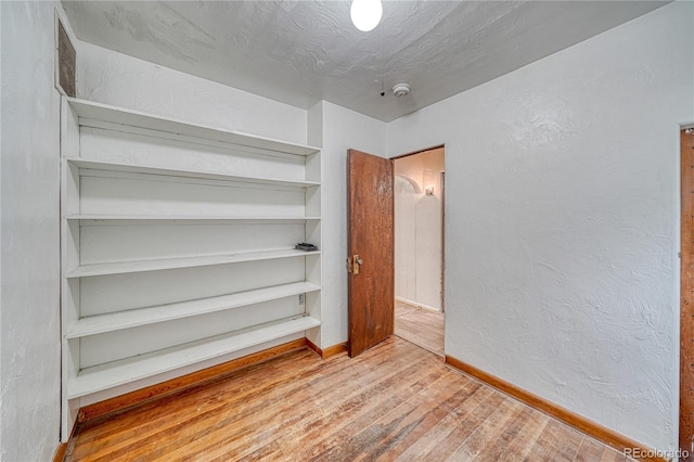 unfurnished room featuring wood-type flooring and a textured ceiling