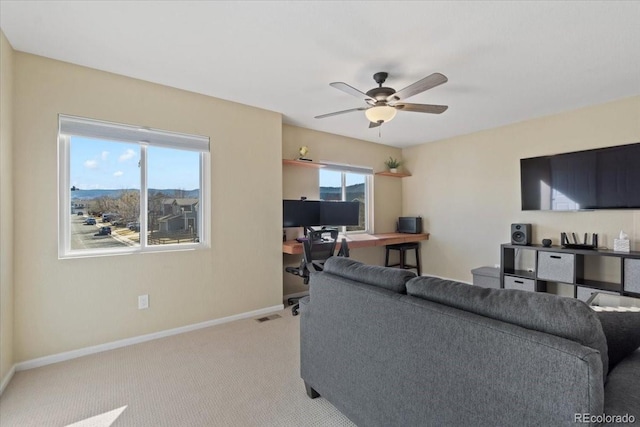 living area with ceiling fan, carpet, and baseboards