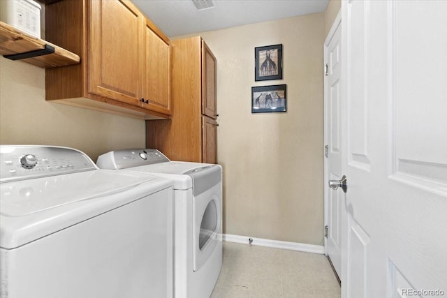 laundry room featuring washing machine and dryer, cabinet space, and baseboards