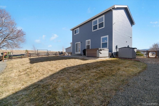 rear view of property featuring fence, a hot tub, central AC unit, and a lawn