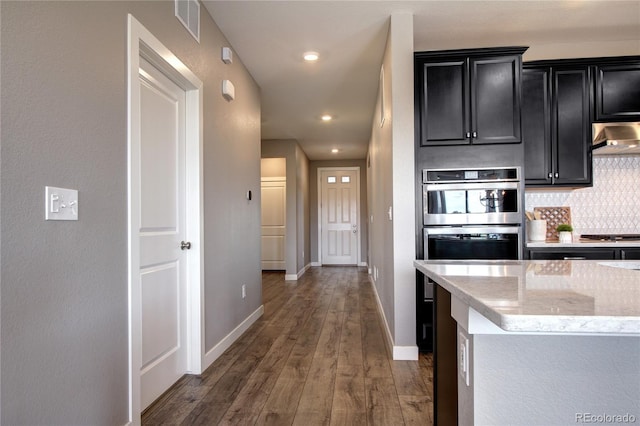 4090 Forever Cir, Castle Rock, CO 80109 - kitchen featuring dark cabinets, under cabinet range hood, decorative backsplash, hardwood / wood-style flooring, and recessed lighting