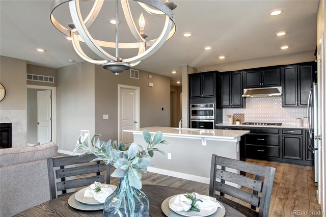 4090 Forever Cir, Castle Rock, CO 80109 - kitchen with appliances with stainless steel finishes, light countertops, dark wood-type flooring, under cabinet range hood, and dark cabinetry