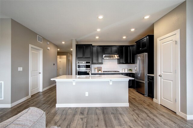 4090 Forever Cir, Castle Rock, CO 80109 - kitchen featuring stainless steel appliances, under cabinet range hood, dark cabinets, light countertops, and recessed lighting