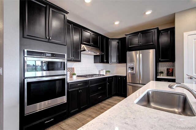 4090 Forever Cir, Castle Rock, CO 80109 - kitchen with stainless steel appliances, a sink, under cabinet range hood, dark cabinets, and recessed lighting