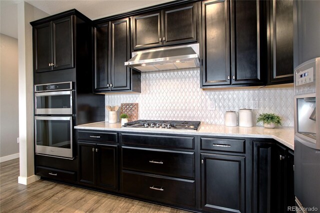 4090 Forever Cir, Castle Rock, CO 80109 - kitchen with under cabinet range hood, appliances with stainless steel finishes, light wood-style floors, and tasteful backsplash