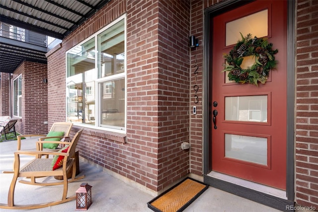 doorway to property with brick siding and a porch