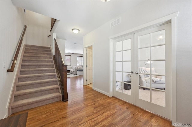 stairs featuring wood-type flooring and french doors