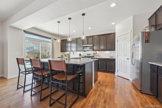 kitchen featuring stainless steel appliances, a kitchen breakfast bar, and a kitchen island with sink