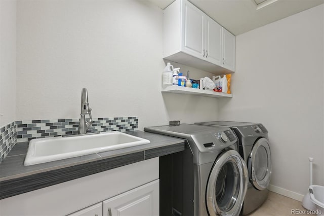 clothes washing area with cabinets, sink, and washer and dryer