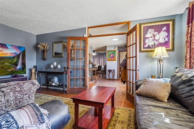 living area with french doors, a textured ceiling, and wood finished floors