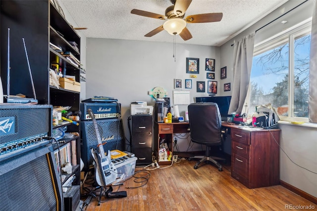 home office with a textured ceiling, wood finished floors, a ceiling fan, and baseboards