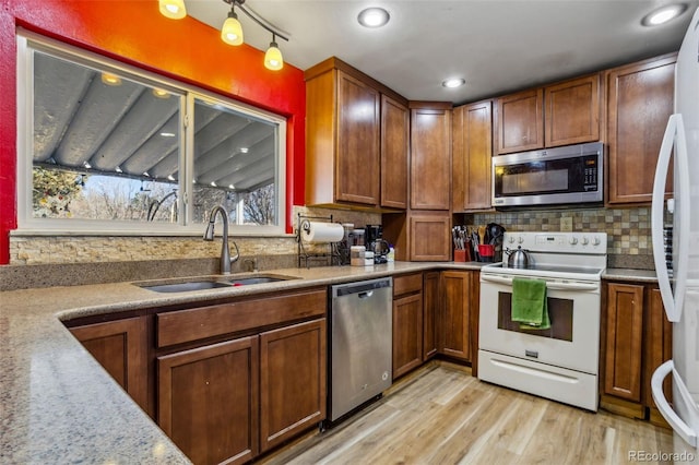 kitchen featuring decorative backsplash, stainless steel appliances, light countertops, light wood-type flooring, and a sink