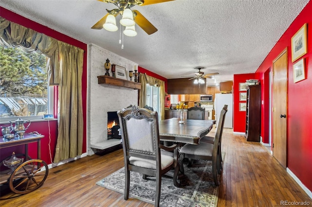 dining space with a brick fireplace, wood finished floors, and a wealth of natural light