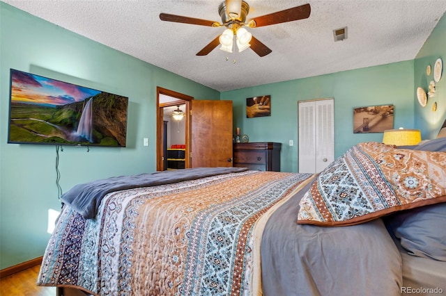 bedroom with baseboards, a ceiling fan, wood finished floors, a textured ceiling, and a closet