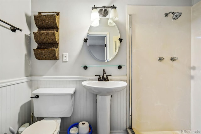 full bathroom featuring a stall shower, wainscoting, and toilet