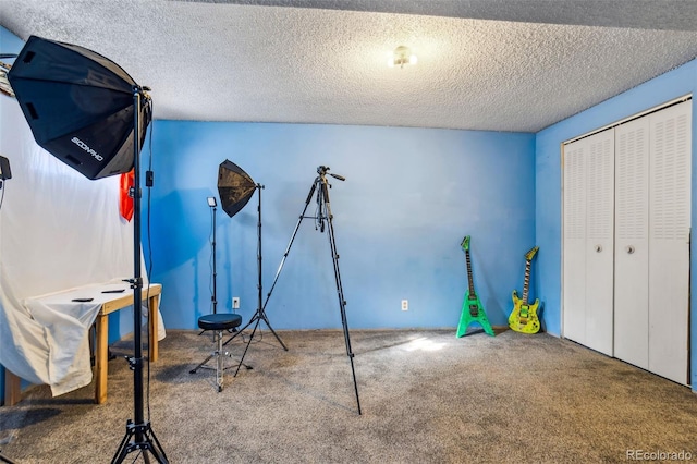 interior space with a textured ceiling and carpet flooring