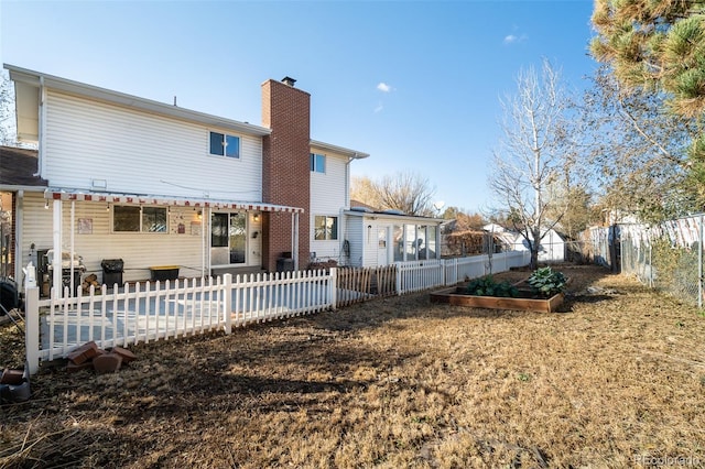 rear view of house with a patio area, a garden, a chimney, and a fenced backyard