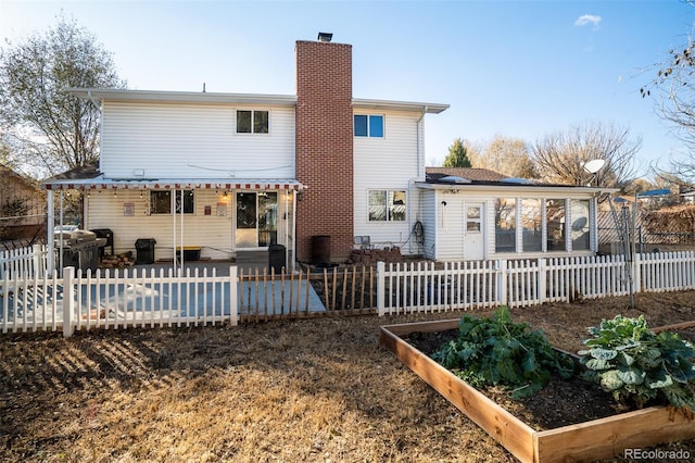 back of property with a chimney, a patio area, fence, and a garden