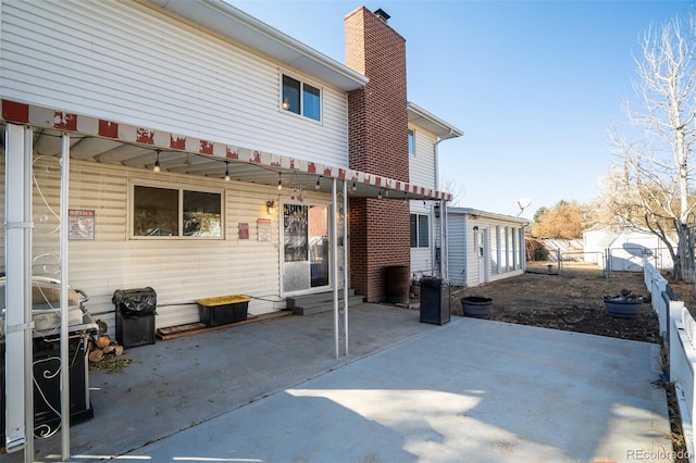 back of property with a patio area, a chimney, and fence