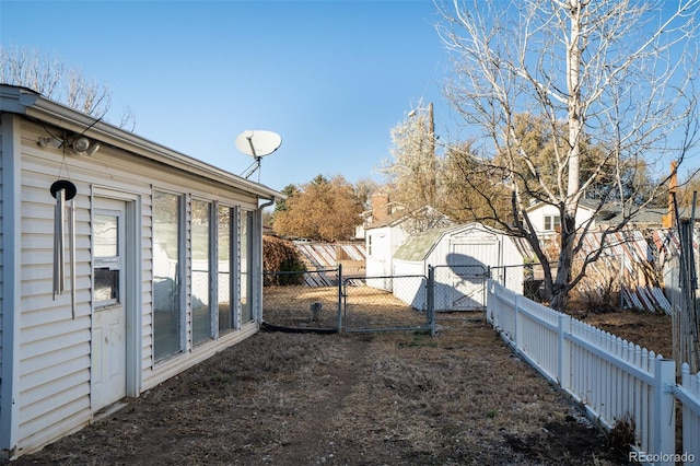 view of yard featuring a fenced backyard, a gate, a storage unit, and an outdoor structure